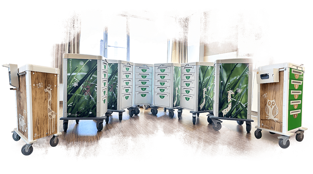 Een rij medische karren in het Groene Hart Ziekenhuis, gezellig gewrapt met houtprints, graspatronen en vrolijke getekende dieren zoals een uil en giraf.