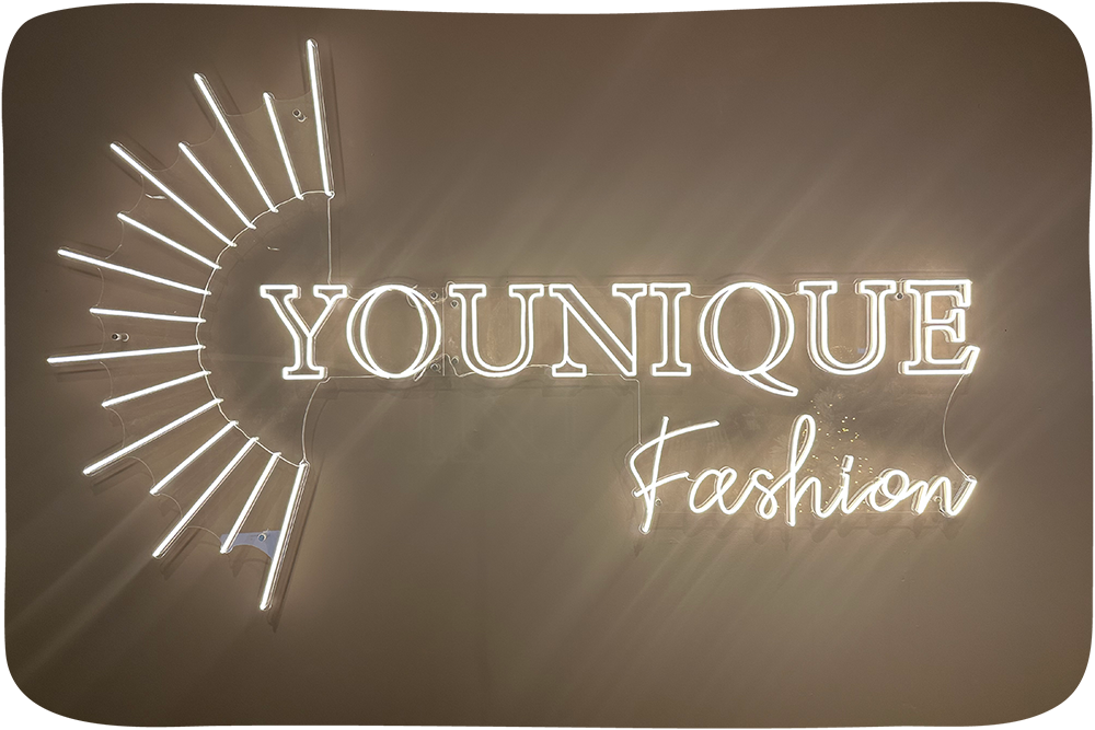 Verlichte LED neon reclame van Younique Fashion, kledingwinkel in Capelle aan den IJssel, met een stralenkrans en de tekst Younique Fashion in warm wit licht